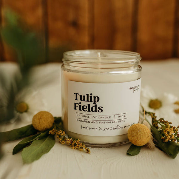Tulip Fields candle on a wooden surface with flowers