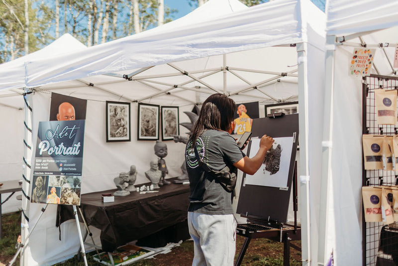 Artist sketching a live portrait at her booth at Summer in Bloom market