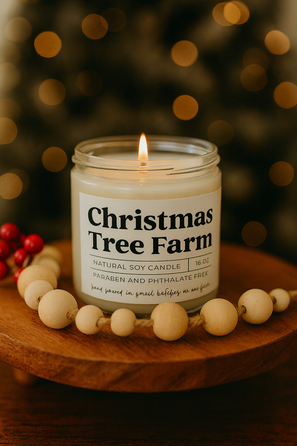 Candle labeled 'Christmas Tree Farm' on a wooden surface with blurred lights in the background